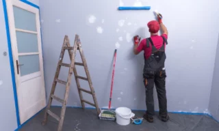 a man patching up the wall before he starts doing the first coating